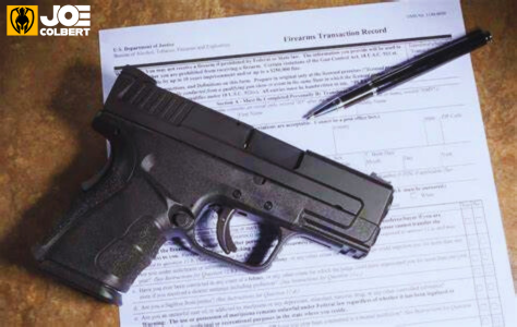 Picture of a handgun on top of ATF required paperwork